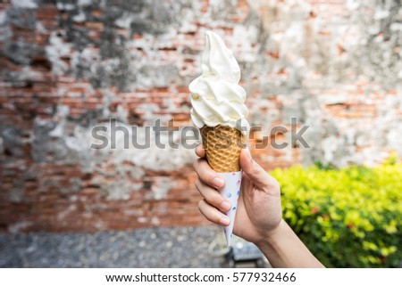 vanilla soft serve held by a hand with old vintage wall in the background