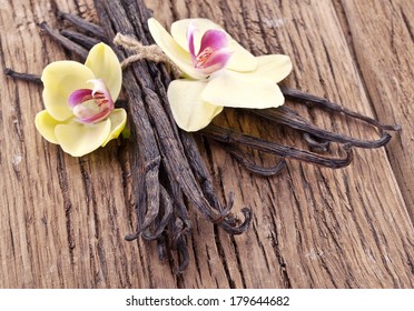 Vanilla sticks with a flower on a wooden table.