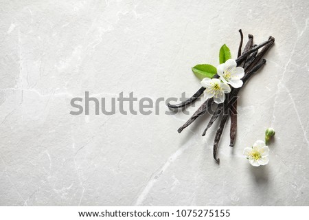 Vanilla sticks and flowers on light background