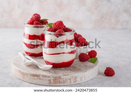 Vanilla white chocolate mousse, trifle, panna cotta or parfait with raspberry sauce in a glass jar. Sweet summer dieting dessert