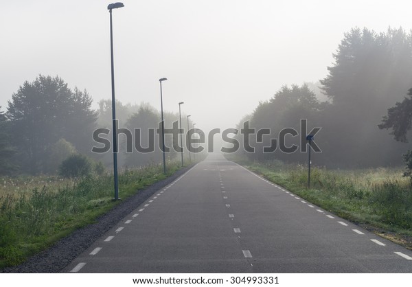 Vanishing in fog bike and pedestrian lane at\
misty morning