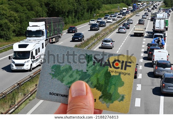 Vannes,\
France, August 7, 2022 :\
Macif insurance member card held in hand\
in close-up with a road in the background\
