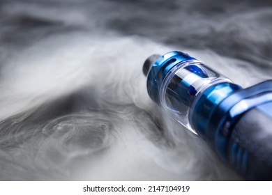 Vape On A Black Background In Smoke, An Electronic Cigarette For Smoking Nicotine, A Lot Of Steam From A Cigarette