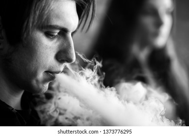 Vape Teenagers. Young Cute Girl In Sunglasses And Young Handsome Guy Smoke An Electronic Cigarettes In The Vape Bar. Bad Habit That Is Harmful To Health. Vaping Activity. Black And White.