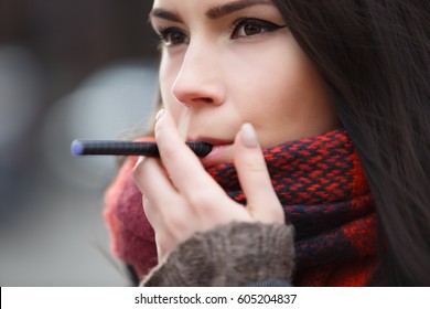 Vaper Girl Smokes Electric Cigarette Device.Sad Young Brunette Woman Smoking Vaporizer With Glycerin Eliquid.Stop Smoking,start Vaping.Portrait Of Beautiful Young Female Smoker