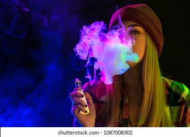 Vaping girl. Young hipster woman vape e-cig on studio on black background. Hip-hop style. Close up.