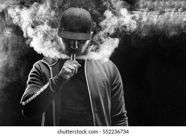 Vaping Man Holding A Mod. A Cloud Of Vapor. Black Background