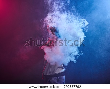 vaping man holding a mod. A cloud of vapor. Black background.