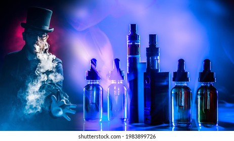 Vaping. VAPE Shop. Young Guy Smokes Vape. Smoking E-cig. Vaper On Dark Background. Smoker On Background Of VAPE Devices. Clouds Of Smoke From Vaping Device. Buying Vaping Juices. Electronic Cigarette