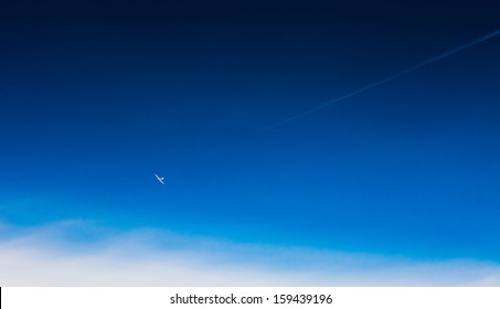 Vapor trail from an airplane in the blue sky, the moon and the plane; light single-engine plane