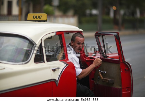 VARADERO, CUBA - OCTOBER 08, 2016: Close-up view\
of taxi driver in his red retro car with open door in the street of\
Varadero