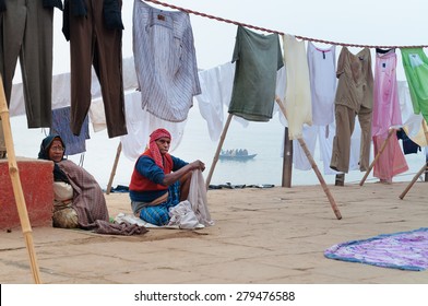 VARANASI, INDIA - DEC 23, 2014: Unidentified Indian Old Family Sit Near Clothesline On Ghat Near Sacred River Ganges In Varanasi. Uttar Pradesh, India 