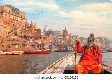 Varanasi, India, January 22,2019: Indian Sadhu baba takes a boat ride on river Ganges overlooking the historic Varanasi city architecture at sunset