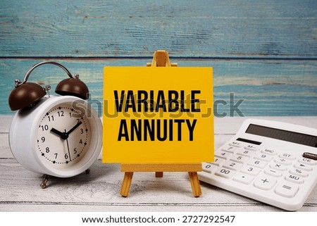 Variable Annuity text written on paper card with calculator and alarm clock on wooden background