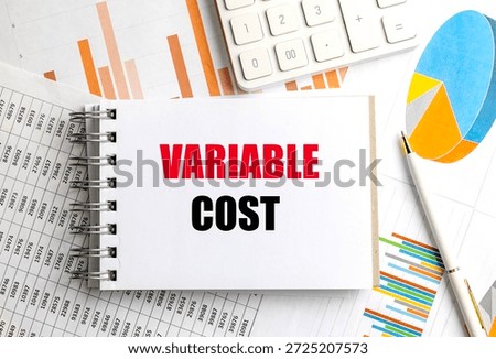 Variable cost phrase on notepad surrounded by financial documents, pen and calculator. 
