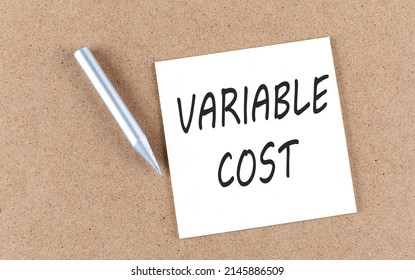 VARIABLE COST text on a sticky note on a cork board with pencil ,