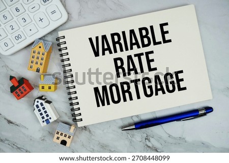 Variable Rate Mortgage text written on notepad with house model on marble background