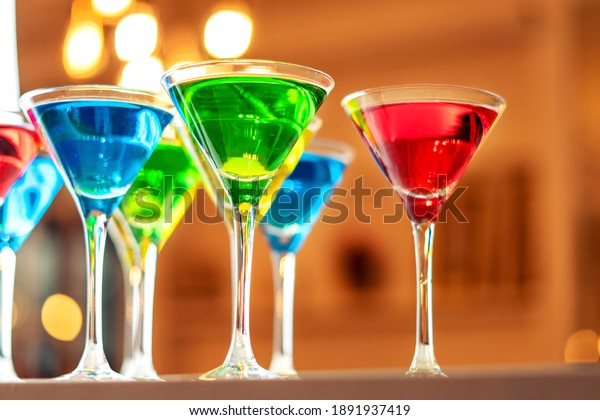 Variation alcoholic\
drinks served on bar counter. Colored drinks in glasses. Beautiful\
background, evening\
mood.