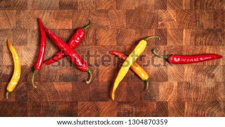 Variation of different color chilli peppers on plate viewed from above.