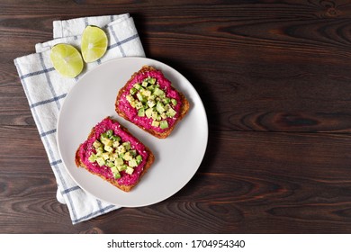 Variation of healthy toasts with avocado beetroot and whole wheat rye  bread  on a plate. Delicious snacks, avocado sandwiches. Food composition, tasty italian meal. Copy space, top view.