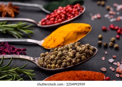 Variation of spices in metal spoons paprika, turmeric, cardamom, a mixture of allspice, thyme, rosemary and salt on a dark concrete background - Shutterstock ID 2254992959