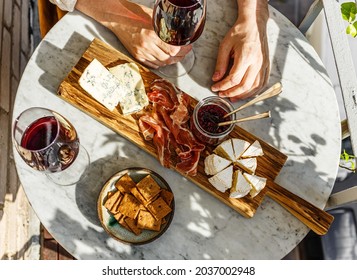 Varied appetizer Cheese board with soft cheese, fruit sauce and red wine on marble table for small party on summer sunny day - Shutterstock ID 2037002948