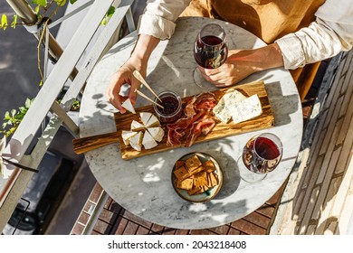 Varied Appetizer Cheese Board With Soft Cheese, Fruit Sauce And Red Wine On Marble Table For Small Party On Summer Sunny Day