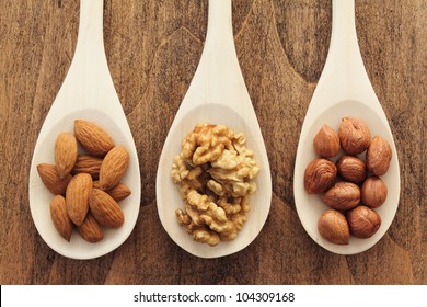 Varieties Of Nuts: Almonds, Hazelnuts And Walnuts In Wooden Spoons.