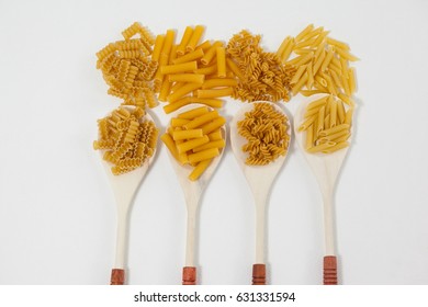 Varieties of pasta spilling out of spoons on white background - Shutterstock ID 631331594
