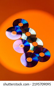 Variety of Arranged CD Disks or DVD Disks on Orange Background With Different Circular Patterns or Masks.Vertical Image Composition