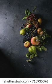 Variety of autumn fruits ripe organic apples, three kind of grapes, pears with leaves over dark texture background. Top view with space. Food background - Shutterstock ID 713935096