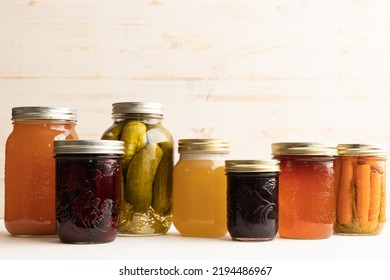 Variety of autumn jars of canning, honey, apple jelly, pickles and pickled carrots and beets against a white wood background with copy space - Powered by Shutterstock