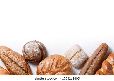 Variety Of Baked Goods On White Background With Copyspace. Bakery Concept - Gold Rustic Crusty Loaves Of Bread And Buns. Still Life Captured From Above (top View, Flat Lay), Banner Layout.