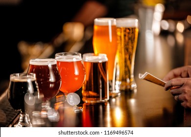 A Variety Of Beer Glasses Lined Up On A Bar