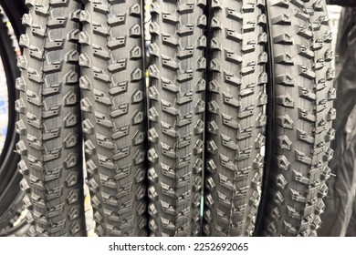A variety of bicycle accessories are on display in a bike shop. The focus is on different types of tires with deep tread patterns. Perfect for off-road adventures