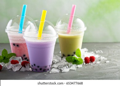 Variety of bubble tea in plastic cups with thick straws