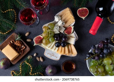 Variety Of Cheese And Fruits Served In Plate As Christmas Tree, On Dark Gray Background With Two Glasses Of Wine. Top View