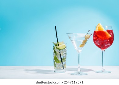 A variety of cocktails arranged on a table against a light blue background, enhanced by sunny glares and playful shadows, with copy space - Powered by Shutterstock