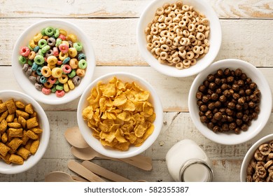 Variety Of Cold Cereals In White Bowls On White Wooden Table, Quick Breakfast For Kids Overhead Shot.