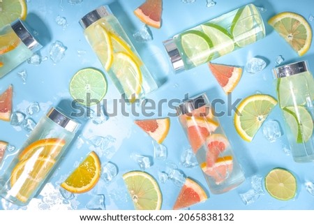 Variety of cold drinks in bottles, summer infused water bottles, lemonade healthy cocktails with different  citrus fruits - lemon, orange, grapefruit, lime, bright background copy space