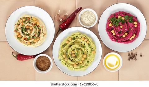 Variety Of Colored Hummus: Red, Green, Yellow - Vegan Lebanese Meal, From Above Overhead Top View, Banner Or Background Texture, Vegan And Vegetarian Protein Food, Assortment Of Bean Meal Concept