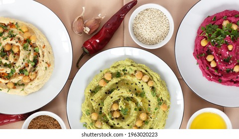 Variety Of Colored Hummus: Red, Green, Yellow - Vegan Lebanese Meal, From Above Overhead Top View, Banner Or Background Texture, Vegan And Vegetarian Protein Food, Assortment Of Bean Meal Concept