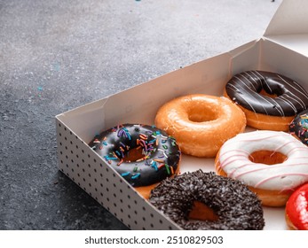 A variety of colorful donuts arranged in a box, featuring a mix of glazed, chocolate-coated, and sprinkled toppings. The assortment includes donuts with vibrant green, white, red, and chocolate - Powered by Shutterstock