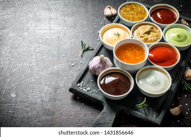 A variety of delicious sauces with slices of garlic. On dark rustic background