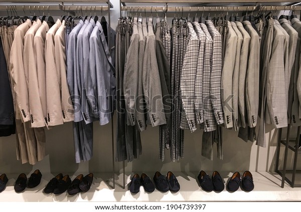 Variety of different striped suit and pants\
hanging on hangers in the\
shop\
\
