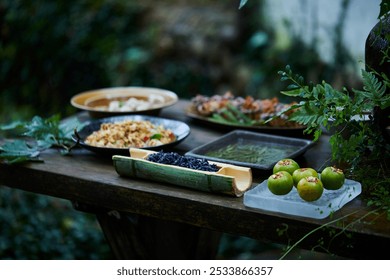 A variety of dishes on a rustic wooden table, with rice in a bamboo tray, grilled skewers, and vibrant green apples, surrounded by lush greenery. - Powered by Shutterstock