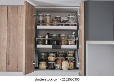Variety of dry foods, grains, nuts, cereals in glass jars in kitchen cupboard. Zero waste storage concept.