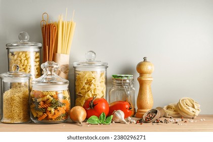 Variety of dry Italian pasta in glass storage glass jars and spices on wooden table. - Powered by Shutterstock