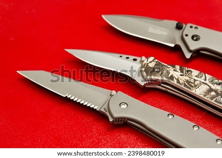 Variety of Folding Knives on Vibrant Red Background in Staggered Formation