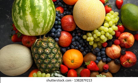 Variety Of Fresh Fruits And Berries On Dark Background: Cantaloupe, Melon, Watermelon, Blueberry, Oranges, Apple, Strawberry, Pineapple, Mango, Grapes And Kiwi.